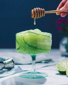 a person holding a wooden spoon over a cucumber