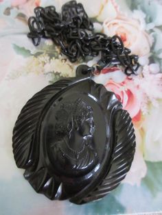 Vintage circa 1930 black celluloid cameo necklace. This vintage 2.5'' black gothic necklace features a large celluloid cameo on a 22'' celluloid link chain. The chain has a hook closure that closes in the front. This estate find is large and wonderful. It wears with a bold style. The cameo has beautiful features and it is beautifully framed on it's carved backdrop. Lovely vintage condition. Vintage Black Medallion Necklace, Vintage Black Cameo Jewelry, Vintage Black Cameo Necklace, Black Cameo Necklace In Vintage Style, Black Cameo Jewelry For Collectors, Black Cameo Medallion Jewelry, Collectible Black Cameo Jewelry, Black Cameo Medallion Necklace, Vintage Black Carved Jewelry