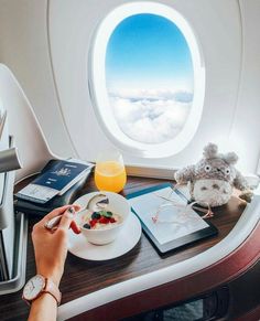 a person is eating breakfast on an airplane with a view of the sky and clouds