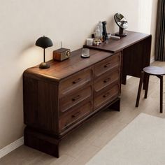 a wooden dresser sitting next to a lamp on top of a hard wood floor near a window