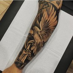 a man's arm with an eagle and cross tattoo on the left side of his arm