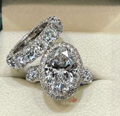 two diamond rings sitting on top of each other in a white box with diamonds around them