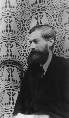 an old black and white photo of a man with a beard sitting in front of a wall