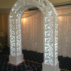 an archway decorated with white paper flowers and lights