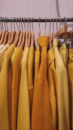 clothes hanging on wooden hangers in front of a wall