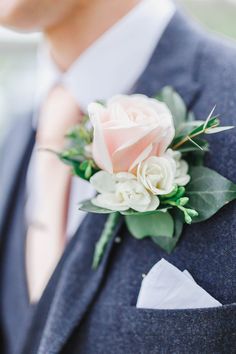 a man in a suit and tie holding a pink rose boutonniere on his lapel