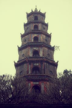 a tall tower with clocks on it's sides and trees in the foreground