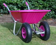 a pink wheelbarrow sitting in the grass