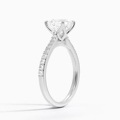 a white gold ring with a princess cut diamond on the side and pave set shoulders