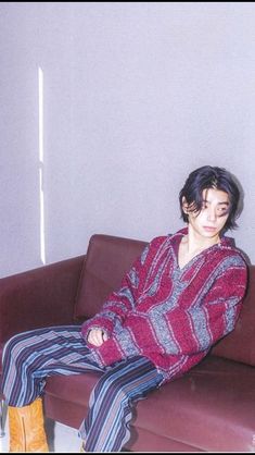 a man sitting on top of a brown couch next to a white wall in a living room