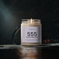 a candle is sitting on a table with a black mug in front of it that says 555 transsemaration