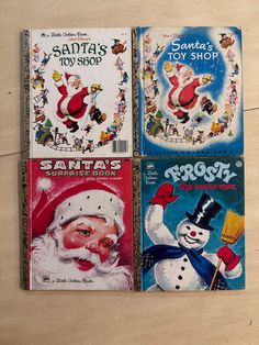 three vintage santa's toys books sitting on top of a wooden table