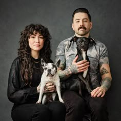 a man and woman sitting next to each other holding small dogs