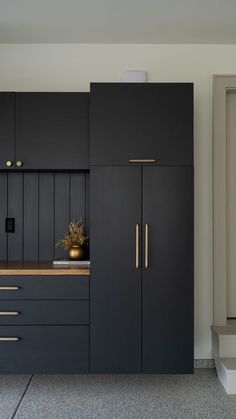 a kitchen with black cabinets and gold handles on the countertop, along with a vase filled with flowers