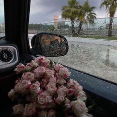 a bouquet of flowers sitting in the passenger seat of a car on a rainy day