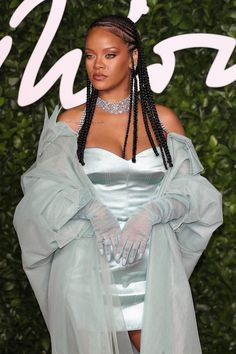 a woman with long braids wearing a blue dress and gloves on the red carpet