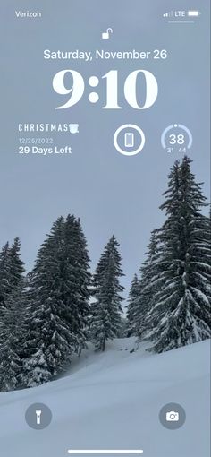 an iphone screen showing the time and weather for christmas in front of snow covered trees