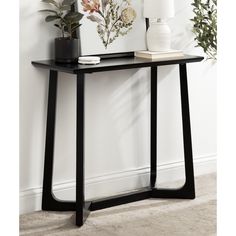 a black console table with flowers on top and a white vase sitting next to it