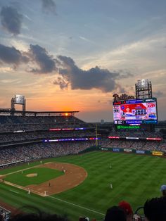 a baseball stadium filled with lots of people watching the sun go down on it's field