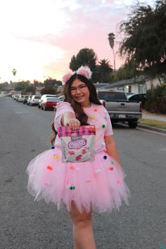 a girl in a pink tutu and dress pointing at the camera with her hand