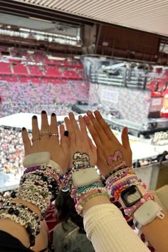 two women with bracelets on their hands in front of a crowd at a sporting event