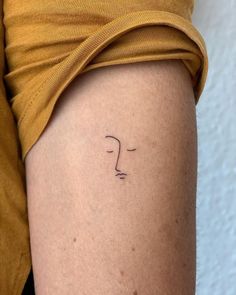 a woman's arm with a small face tattoo on the left side of her thigh