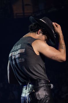 a man with a hat on his head is standing in front of a crowd at a concert