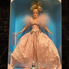 a barbie doll in a pink dress and feathered headdress is shown inside a blue box