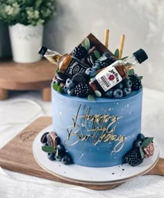 a blue birthday cake with liquor and berries on top