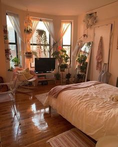 a bedroom with hardwood floors and lots of plants in the window sill, along with a bed