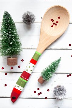 a wooden spoon sitting on top of a table next to christmas trees and decorations with glitter balls around it