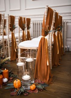 the chairs are decorated with orange sashes and candles