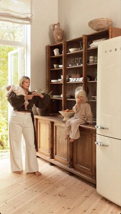 an older woman standing in front of a refrigerator