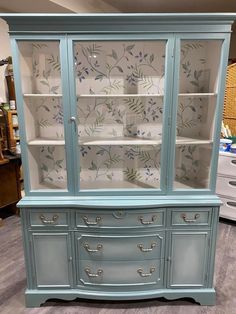 a blue china cabinet with flowers painted on it