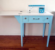 a sewing machine sitting on top of a blue table next to a white wall and wooden floor