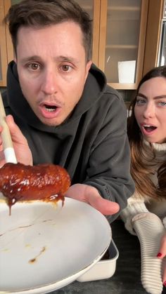 a man holding a plate with a hot dog on it and a woman looking at the camera