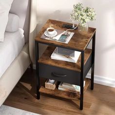 a small table with some books and a cup of coffee on it next to a bed