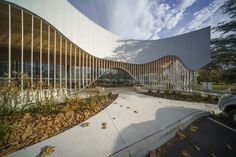 the curved building has many windows on it's sides and is surrounded by leaves