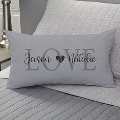 a bed with two pillows and a pillow that says love in black on the front