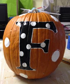 a pumpkin with polka dots and the letter f painted on it's side sitting on a table