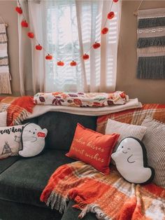 a couch with pillows and blankets on it in front of a window filled with curtains