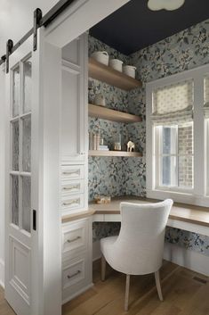 a white chair sitting in front of a window next to a desk and bookshelf