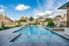 an outdoor swimming pool with water features in the foreground and houses in the background