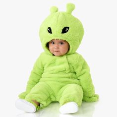 a baby in a green costume sitting on the floor