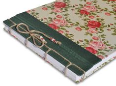 an open book with flowers on it and ribbon tied to the front cover, sitting on a white surface