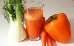 carrots, celery and an orange juice are on the table next to each other