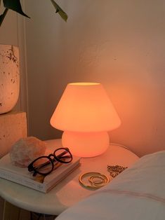 a lamp that is on top of a table next to a book and some glasses