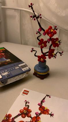 a laptop computer sitting on top of a table next to a vase with red flowers