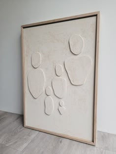 a white framed artwork with footprints and heart shapes on the wall next to a wood floor