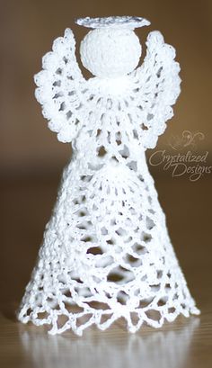 a white crocheted angel figurine sitting on top of a wooden table